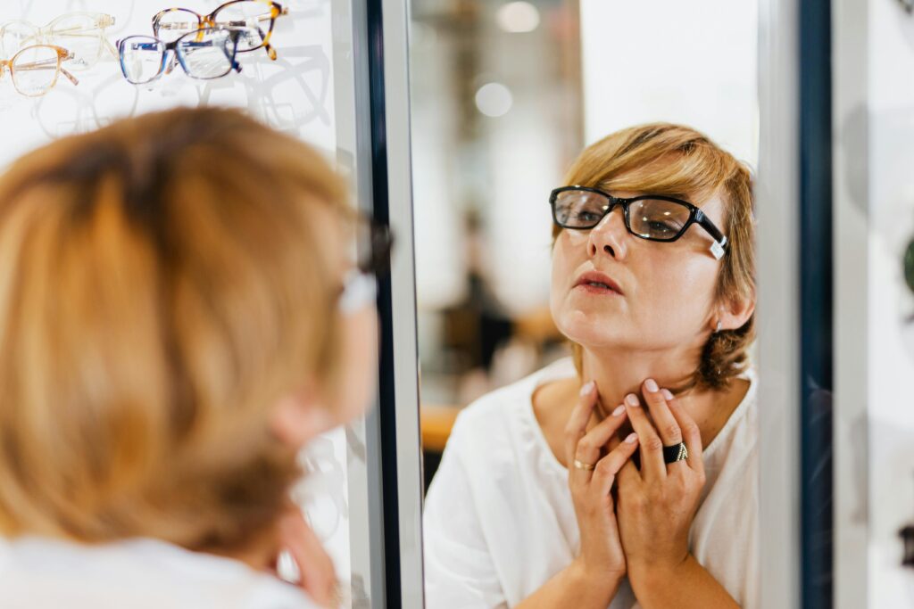 pexels-photo-5201931-5201931 A woman examines her reflection while trying on eyeglasses in an optical store.